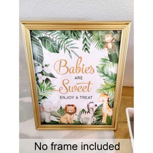 Puede incluir: Un cartel enmarcado en dorado con fondo blanco y hojas verdes de acuarela. El cartel dice "Babies are Sweet" con las palabras "Enjoy a Treat" debajo. Hay imágenes de un mono, un elefante, un león, una cebra y una jirafa en el cartel.