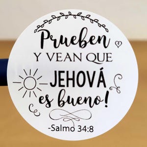 May include: White round sticker with black text that reads "Prueben y vean que Jehová es bueno! -Salmo 34:8". The text is in a decorative font and includes a small sun and a heart symbol.