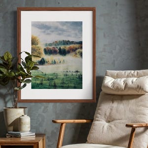 May include: A framed landscape painting depicts a misty meadow with trees in autumn colors. The artwork is in a brown wooden frame, hanging on a textured gray wall. A potted plant and a chair are in the foreground.