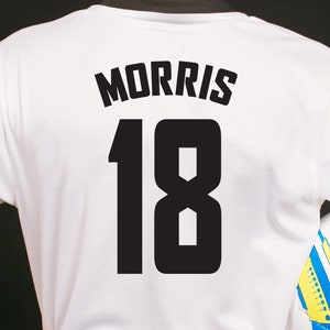 White soccer jersey with black text and numbers. The text reads "MORRIS" and the number is "18".