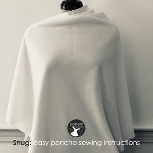 May include: A white poncho with a simple design. The poncho is draped over a mannequin and has a logo that says "pattern division" with a stylised bird design.