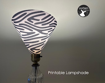 May include: A black and white zebra-print lampshade with a cone shape. The lampshade is attached to a clear glass lamp base. The text "Printable Lampshade" is visible below the lamp.