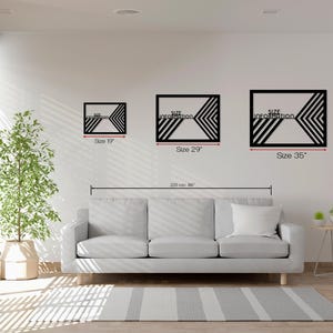 May include: Three black geometric wall art pieces with chevron designs are displayed on a white wall. The sizes are 19 inches, 29 inches, and 35 inches. The text "Size Information" is visible on each piece. A gray sofa and rug are in the foreground.