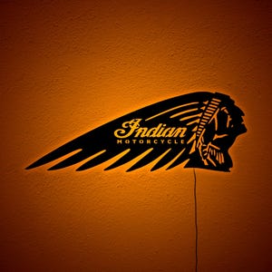 May include: Black metal Indian Motorcycle logo with a Native American headdress design. The logo is illuminated with a warm orange glow, and the words "Indian MOTORCYCLE" are visible.