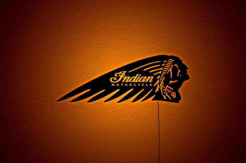 May include: Black metal Indian Motorcycle logo with a Native American headdress design. The logo is illuminated with a warm orange glow, and the words "Indian MOTORCYCLE" are visible.
