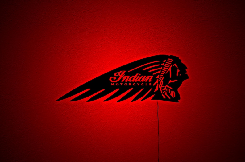 May include: Black Indian Motorcycle logo with red neon lighting. The logo features a stylized Native American headdress and the words "Indian MOTORCYCLE" in a script font. The image is set against a red background.