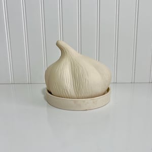 May include: A white ceramic mug with a black handle and the text "But First, Coffee" in a bold, black font. The mug is set against a blurred background, suggesting a cozy setting.