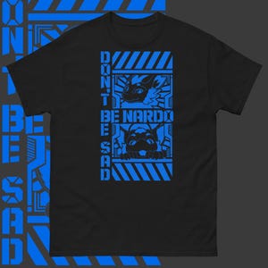 Peut inclure: T-shirt noir avec un motif graphique bleu. Le graphique présente deux personnages de dessin animé avec le texte "Don't Be Nardo Be Sad" dans une boîte à rayures bleues et blanches.