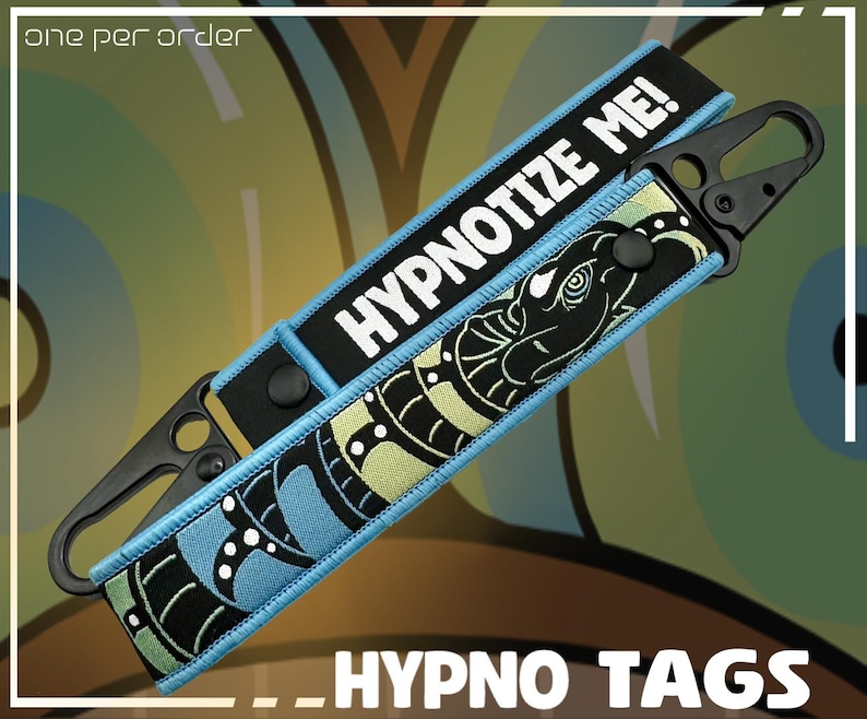 May include: Two black and blue Hypno Tags with a black clasp. One tag reads "HYPNOTIZE ME!" in white text. The other tag features a black and green snake design. The words "_HYPNO TAGS" are at the bottom of the image.