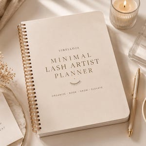 May include: A beige spiral-bound planner with gold detailing, labelled "Minimal Lash Artist Planner." The image includes a lit candle, a pen, false eyelashes, and a card with the text "Focus, Plan, Grow, Repeat."