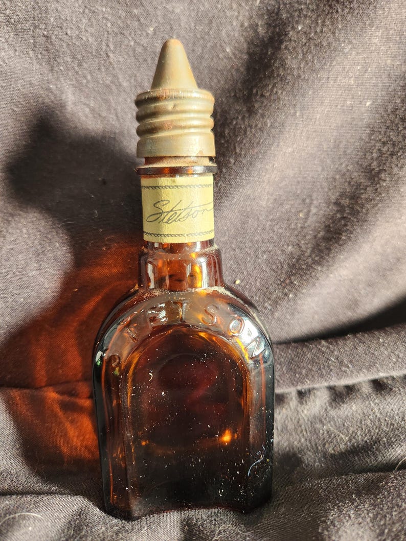 Pu&ograve; includere: Piccola bottiglia di vetro marrone con tappo in metallo. L'etichetta recita "Stetson". Probabilmente per colonia o profumo. Articolo vintage.