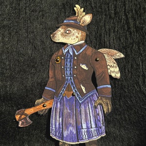 May include: A papercraft figurine of a deer wearing a brown jacket, blue and white patterned vest, purple skirt, and a brown hat with antlers. The deer is holding an axe in its right hand.