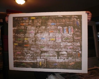 May include: A close-up image of a stone wall with colorful paper notes stuck to it. The wall is made of large, rough stones and has a textured surface. The notes are arranged in a random pattern and are mostly rectangular in shape. Some of the notes are folded in half, while others are flat. The notes are in various colors, including red, blue, green, yellow, and orange.