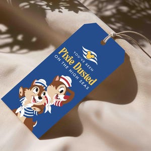 Puede incluir: Una etiqueta de regalo rectangular azul con un cordel, que muestra dos ardillas de dibujos animados con trajes de marinero. El texto "YOU'VE BEEN PIXIE DUSTED ON THE HIGH SEAS" aparece en amarillo y blanco, con un icono amarillo de Mickey Mouse.