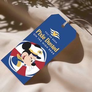 May include: A rectangular blue gift tag with a string, featuring a graphic of Mickey Mouse in a captain's uniform inside a red and white life preserver. The text reads "YOU'VE BEEN PIXIE DUSTED ON THE HIGH SEAS" with a cruise ship logo.