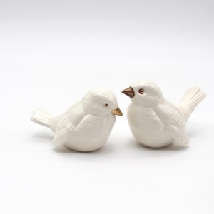 May include: A white ceramic mug with a black handle and the text "But First, Coffee" in a handwritten style. The mug is on a white surface. The mug is approximately 4 inches tall.