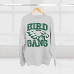 May include: A grey sweatshirt with a green eagle graphic and the text "BIRD GANG" in a collegiate font.