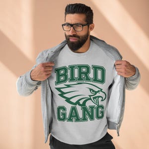 May include: A grey sweatshirt with a green eagle graphic and the text "BIRD GANG" in a collegiate font.