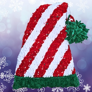 May include: A red and white striped crocheted hat with a green pom-pom. The hat is made with a fuzzy yarn and has a green band at the bottom.
