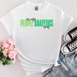 Puede incluir: Camiseta blanca con texto verde y negro que dice "in my people analytics era".