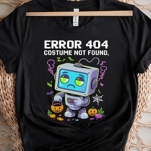 Pode incluir: Camiseta preta com um design de robô de desenho animado e o texto "ERROR 404 COSTUME NOT FOUND". O robô tem um rosto de tela e segura uma cesta de abóbora. Gráficos temáticos de Halloween, incluindo abóboras e uma teia de aranha, cercam o robô.