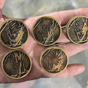 Könnte beinhalten: Fünf bronzefarbene, kreisförmige Münzen mit einem detaillierten Dinosaurier-Design. Jede Münze zeigt einen anderen Dinosaurierkopf oder -körper vor einem strukturierten Hintergrund. Die Münzen haben einen dekorativen, geriffelten Rand.