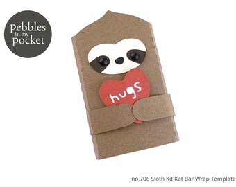 May include: A brown sloth holding a red heart that says "hugs" on it. The sloth is holding the heart in front of its chest. The sloth is made of paper and is part of a kit to make a Kit Kat bar wrapper.