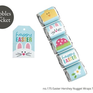 May include: A set of six printable Easter Hershey's Nugget wrappers featuring a blue background with various Easter-themed designs, including a chick, bunny, and a flower. The wrappers also include the text "Happy Easter" in rainbow colors.
