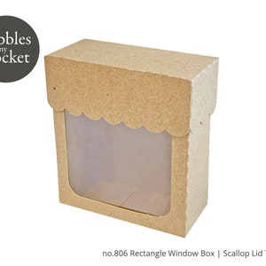 Puede incluir: Una caja de cartón marrón con una tapa festoneada y una ventana transparente. La caja está etiquetada "no. 806 Rectangle Window Box | Scallop Lid Template".