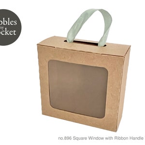 Puede incluir: Una caja de cartón marrón con una ventana cuadrada y un asa de cinta verde claro. La caja tiene el texto "Pebbles in my pocket" impreso en la parte delantera. El texto "no. 896 Square Window with Ribbon Handle Template" está impreso debajo de la caja.