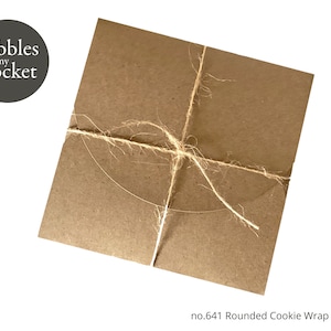 以下が含まれることがあります： 「Pebbles in my Pocket」と「no. 641 Rounded Cookie Wrap Template」のラベルが付いた、麻ひもで結ばれた茶色の紙の包み。