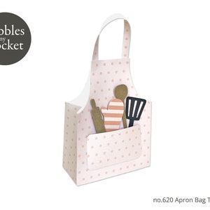 Peut inclure: Un sac à tablier rose et blanc à pois avec une poche et une poignée. Le sac est rempli d'ustensiles de cuisine, dont un rouleau à pâtisserie, une spatule et un gant de cuisine.