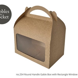 May include: A brown gable box with a round handle and a clear rectangular window. The box has the text "Pebbles in my pocket" on the front.