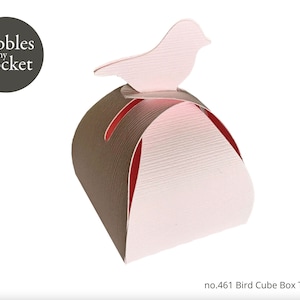 Może przedstawiać: Szablon pudełka w kształcie sześcianu z ptakiem, wykonany z różowego i brązowego papieru, z tekstem "Pebbles in my pocket" i "no.461 Bird Cube Box Template".