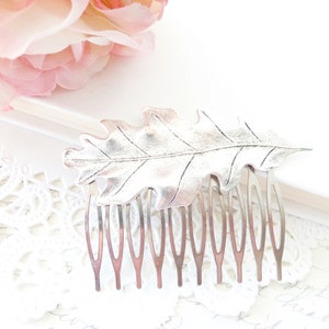 May include: Silver hair comb with an oak leaf design. The comb has a silver finish and is made of metal.
