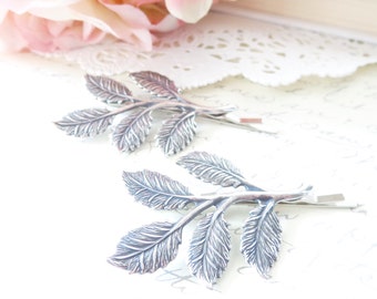 May include: Two silver leaf hair clips with a delicate, detailed design. The clips are perfect for adding a touch of elegance to any hairstyle.