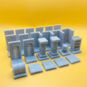 Op de afbeelding: Een verzameling grijze miniatuur kerkerterreinonderdelen, waaronder muren, pilaren, deuren, een vat en een boekenplank. De stukken zijn gerangschikt op een gele ondergrond, perfect voor tabletop gaming of modelbouw.