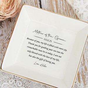 May include: White ceramic ring dish with a gold trim and the text "Mother of the Groom 03.12.25 Because of you, my life is filled with more joy. Thank you for guiding your son into the remarkable man he is today. I am not only blessed with the love of my life, but also the gift of loving you. Love Helen"