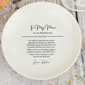 Peut inclure: Un plat à bague en céramique blanche avec un message doux pour une mère le jour du mariage de sa fille. Le message dit : "To My Mom On my Wedding day 03.12.25 You held my hand for many years, supported me through joy and tears, and though I'm grown and on my own, my heart will always be tied to you. Thank you for your unending support, guidance, patience, and infinite love. Today a bride, tomorrow a wife, forever your little girl Love. Helen"