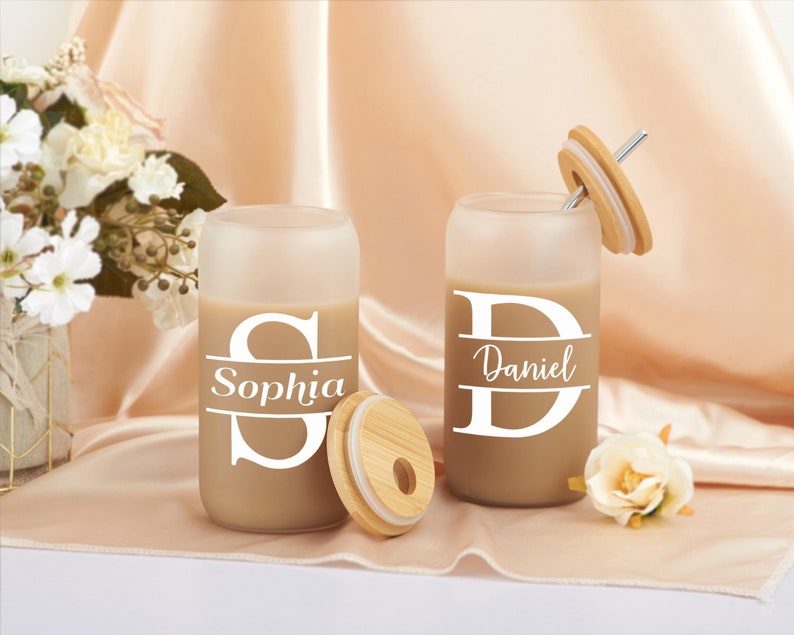 Pode incluir: Dois copos de vidro fosco com tampas e canudos de bambu. Os copos t&ecirc;m os nomes "Sophia" e "Daniel" escritos com a letra inicial em um tipo de letra grande.