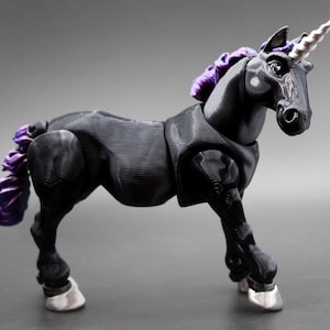Puede incluir: Una figura de unicornio negro con cuerno blanco y crin y cola moradas. El unicornio tiene pezuñas plateadas y está posado sobre una superficie gris. La figura es un modelo tridimensional detallado.