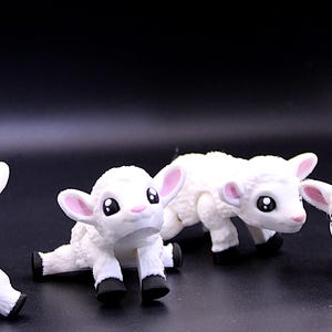 May include: Four white plush toy lambs in different poses. The lambs have pink ears and black eyes.
