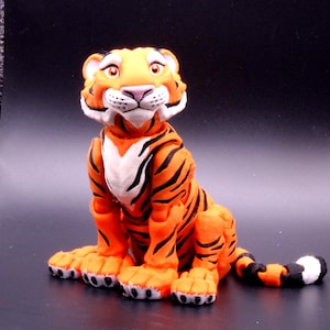 May include: A hand-painted orange and black tiger figurine with white accents. The tiger is sitting with its head tilted up and its mouth slightly open.
