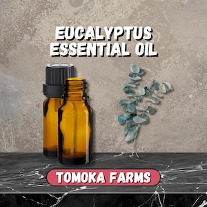 May include: Two amber glass essential oil bottles with black caps, next to a sprig of eucalyptus leaves. The text "EUCALYPTUS ESSENTIAL OIL" is at the top, and "TOMOKA FARMS" is at the bottom.