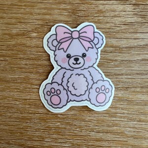 Sticker flirt violette teddybeer | Roze lint en pootjes | Zachte esthetiek voor meisjes | Leuke pastelkleurige sticker van 6 x 5,5 cm voor laptop, dagboek of spiegel