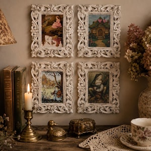 May include: Four rectangular wall frames with ornate, distressed white scrollwork borders. Each frame contains a different illustration: a girl by a pond, a cottage with heart-shaped trees, a small creature in a landscape, and a frog playing a banjo.