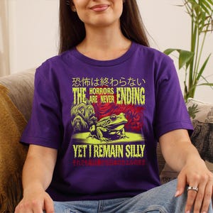 May include: Purple t-shirt featuring a green frog and the text "The horrors are never ending, yet I remain silly" in Japanese and English.