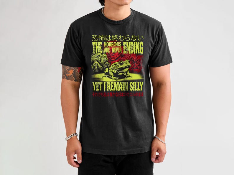 May include: Black t-shirt with a green and red graphic of a frog and the text "The horrors are never ending, yet I remain silly". The text is in Japanese and English.