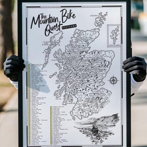 Op de afbeelding: Een ingelijste zwart-witkaart getiteld The Mountain Bike Quest Scotland, met een gedetailleerde illustratie van het Schotse landschap, diverse locaties voor mountainbikeroutes, een genummerde lijst met trailnamen en de Shetlandeilanden.