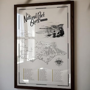 May include: A framed black and white map titled The National Park Quest Victoria. The print features a detailed illustration of the state of Victoria, Australia, including a compass rose, a list of national parks, and a sketch of hikers.